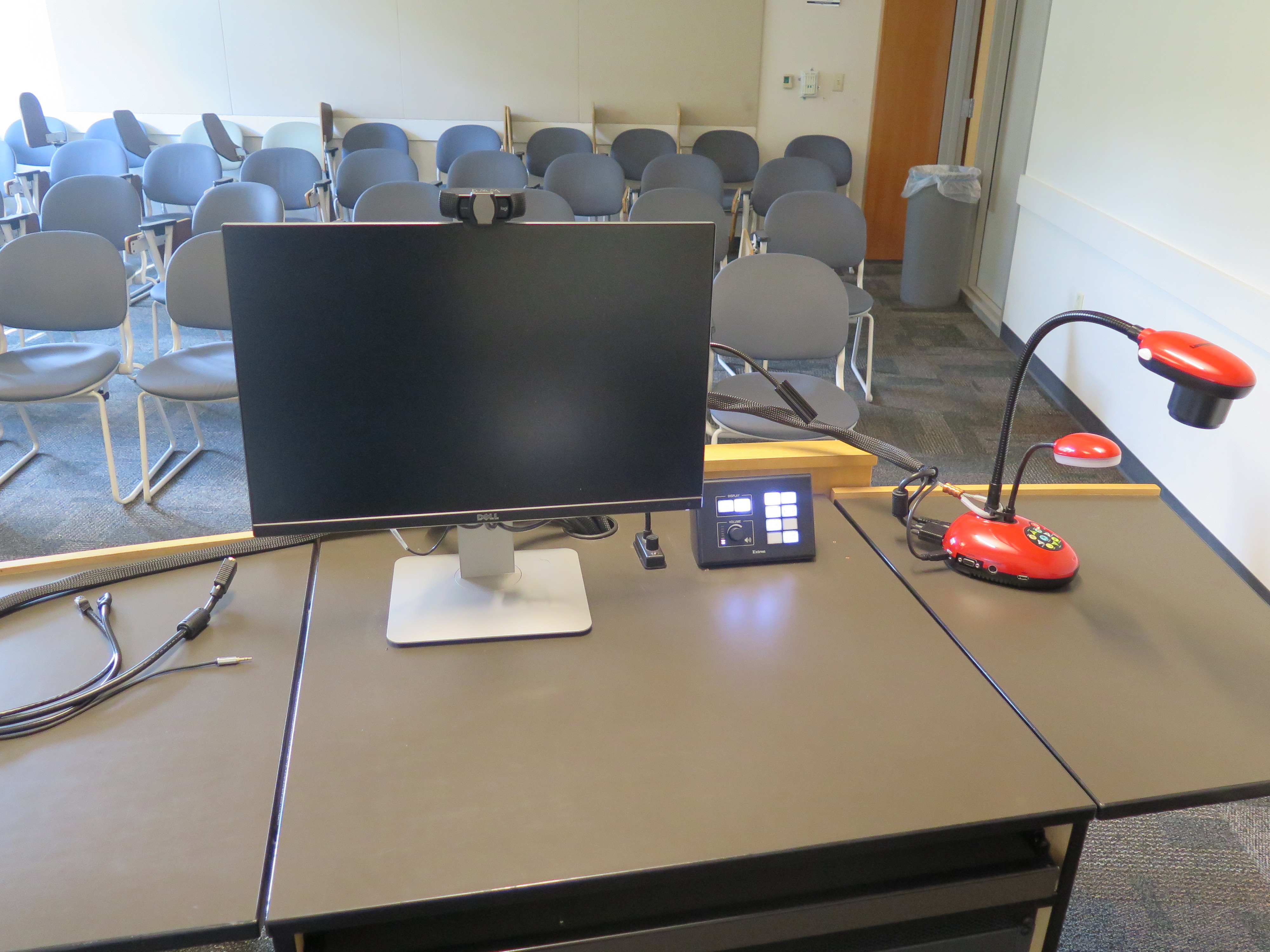 On top of Podium is Logitech 920 Webcam, Dell Computer Monitor, AV Push Button Controller, and Lumens Ladybug Document Camera.