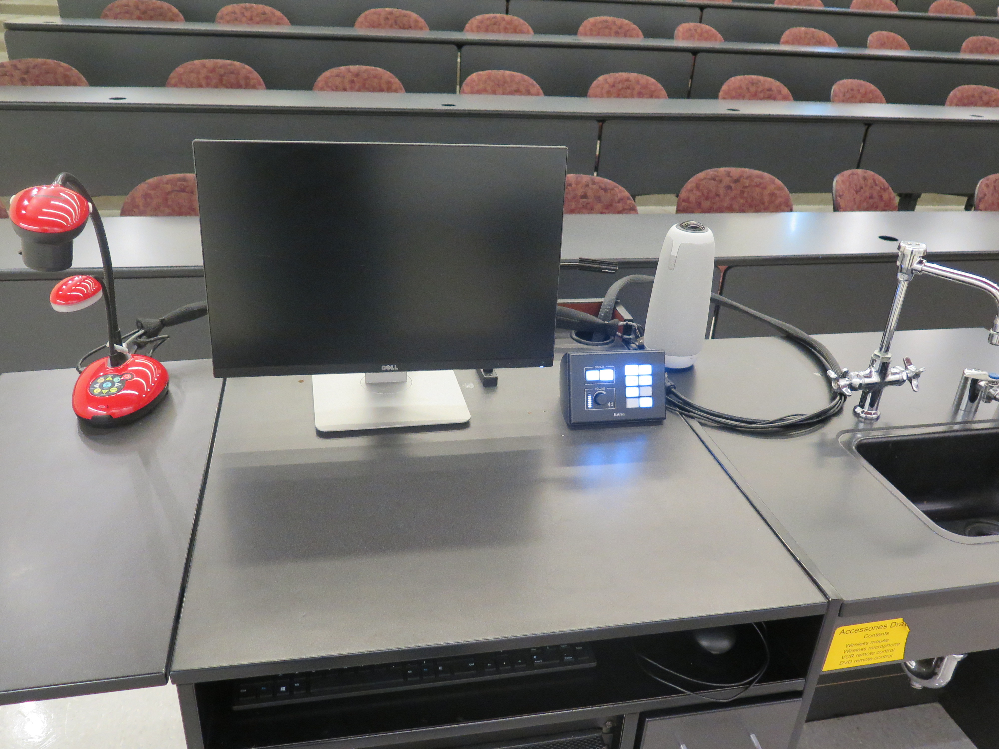 On top of podium is Owl Camera, Dell computer monitor, AV push button controller, and Lumens Ladybug document camera.