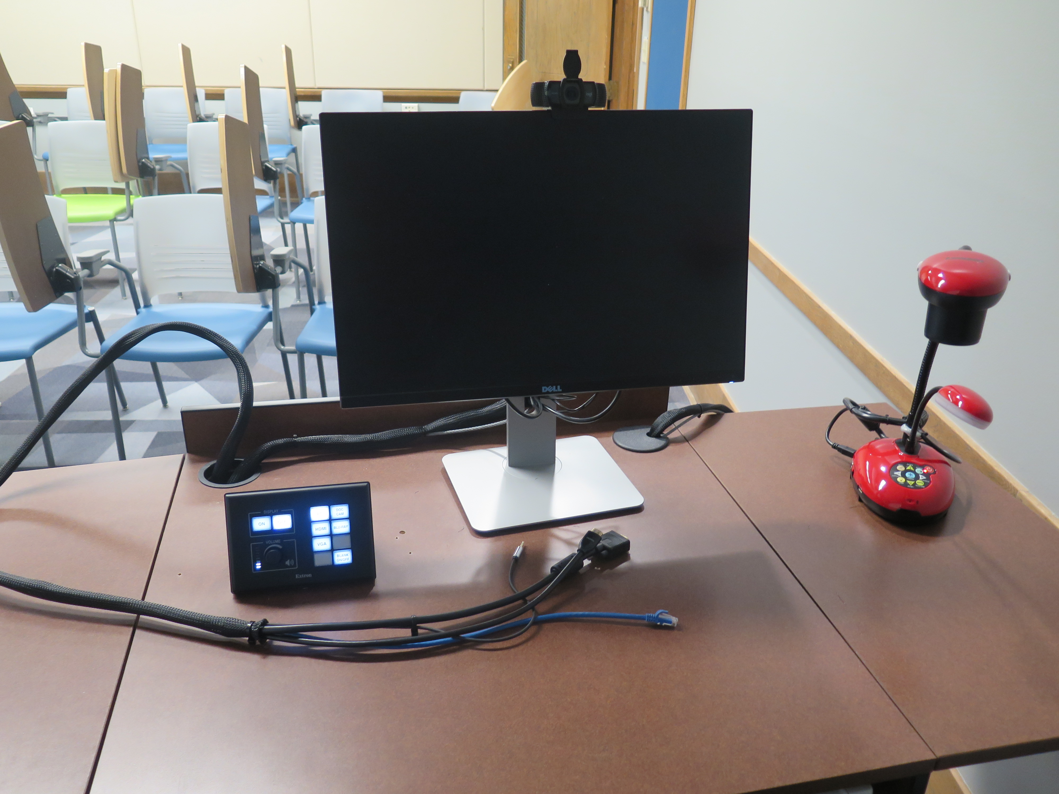 On top of Podium is Logitech 920 Webcam, Dell Computer Monitor, AV Push Button Controller, and Lumens Ladybug Document Camera.