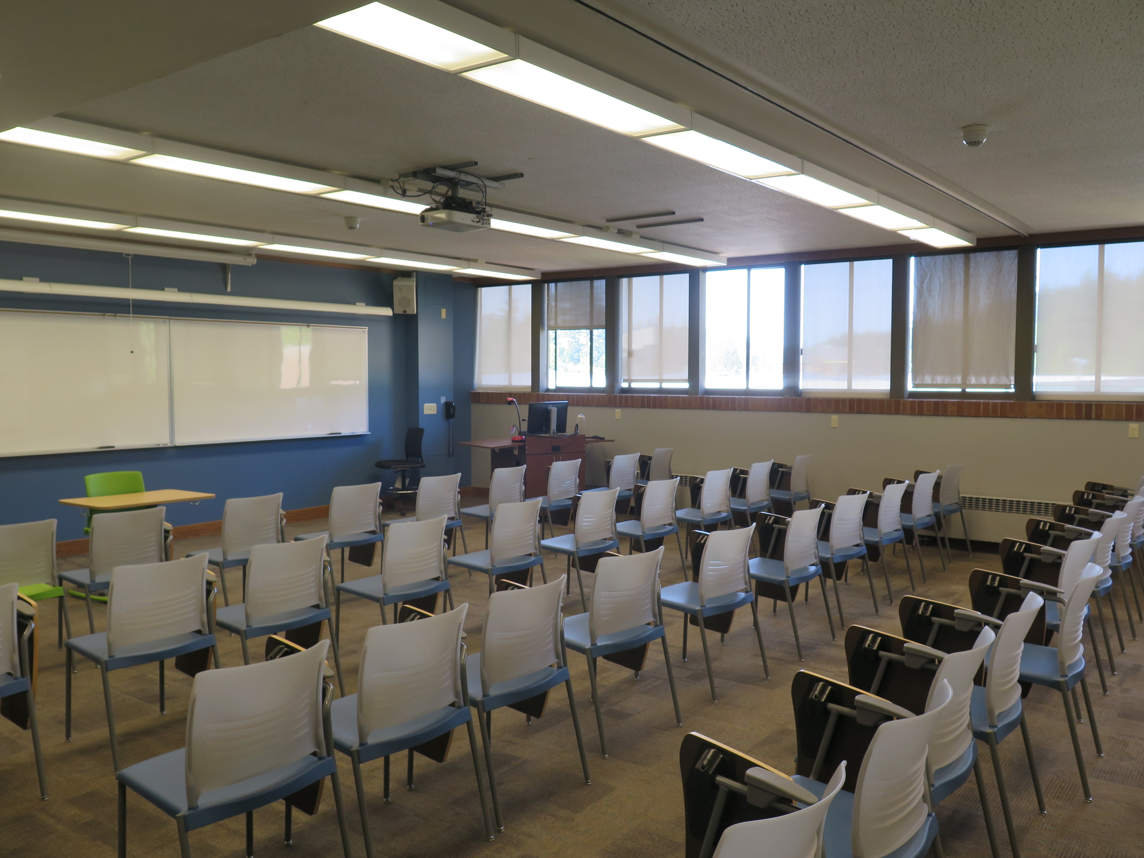 This room contains carpet floor, Moveable Tablet armchairs, whiteboard at the front of the room and a podium. 