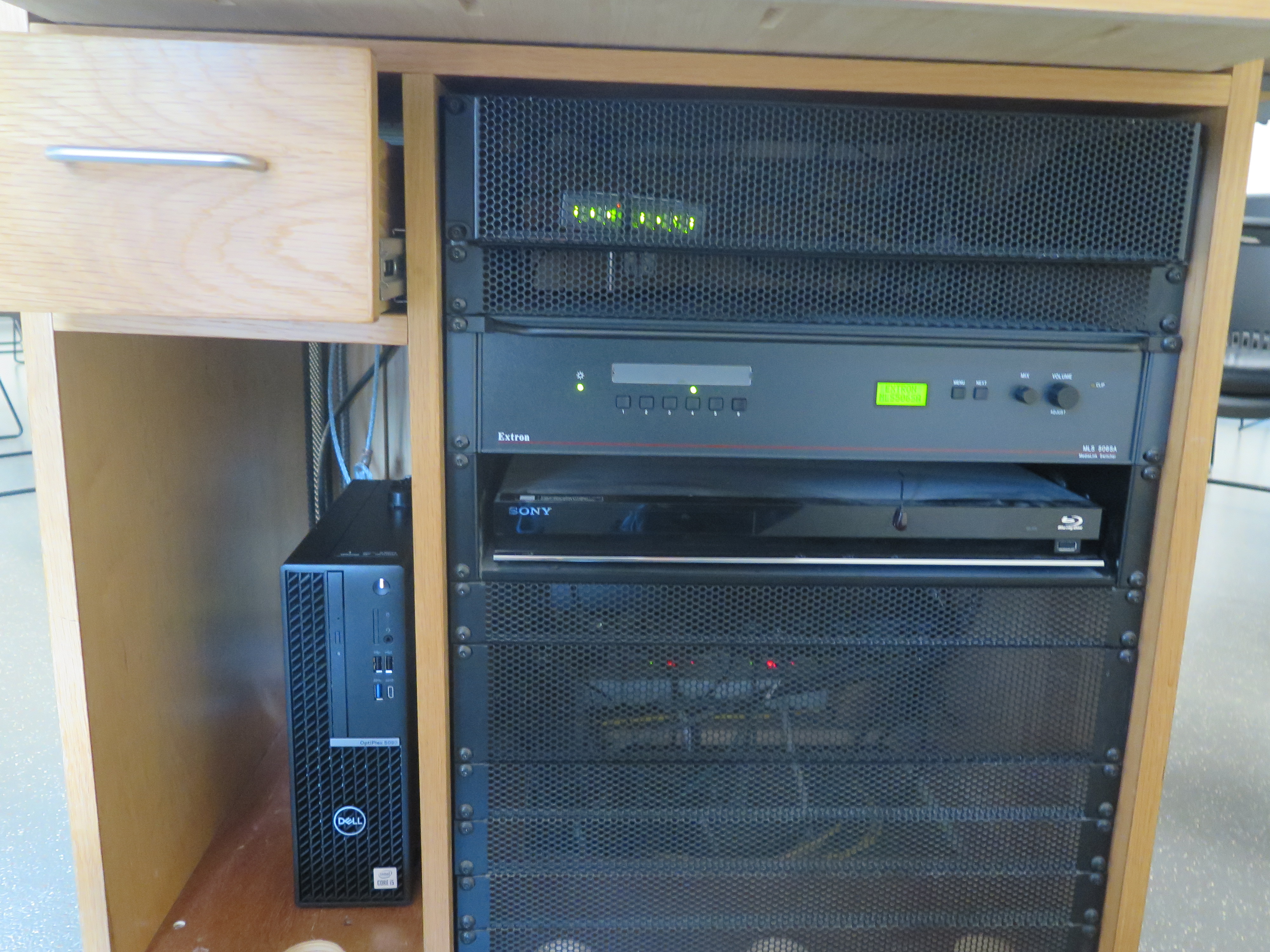 front of equipment rack showing AV switcher, below that is blue-ray player, below that is the dell computer CPU