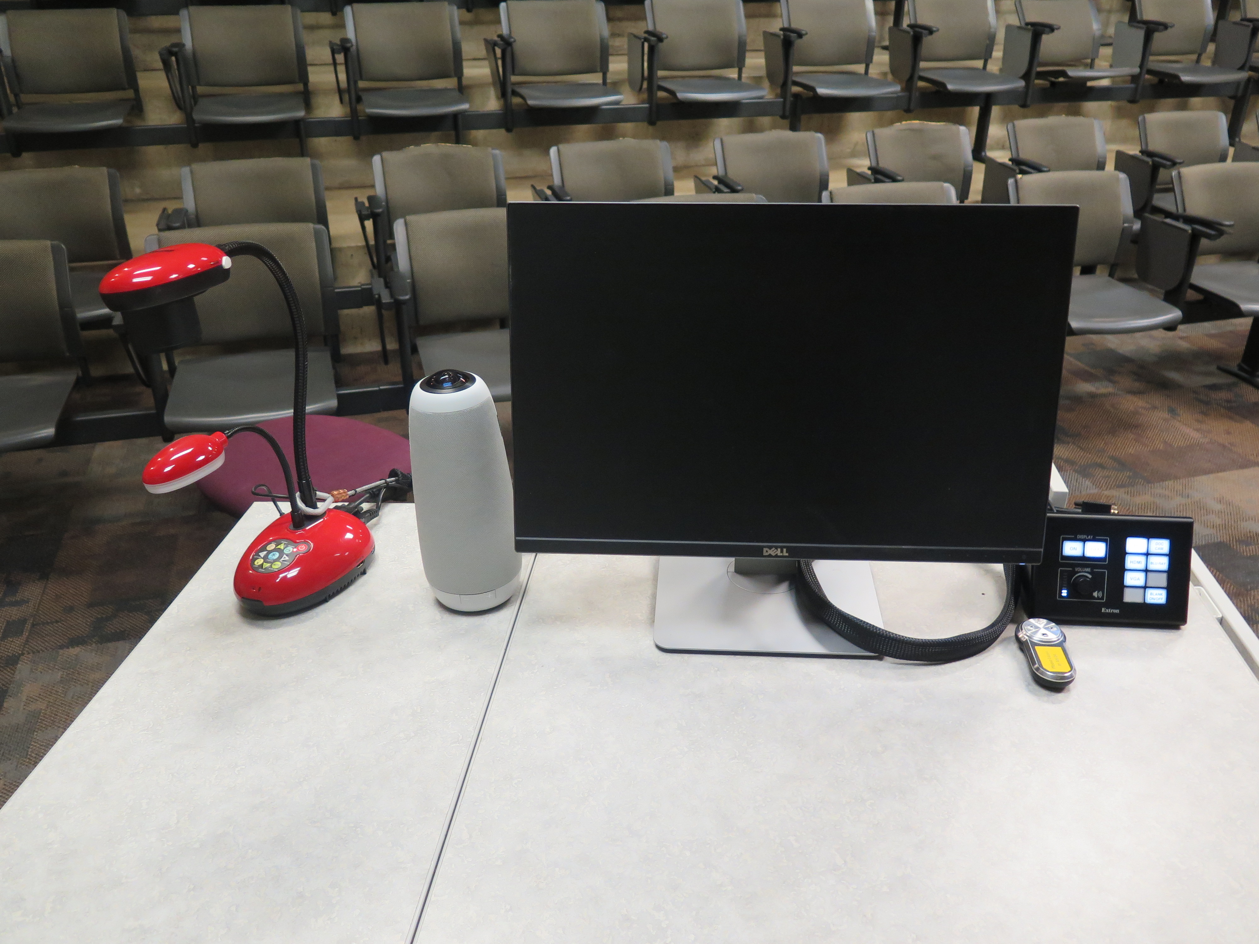 On top of Podium is Owl webcam, Dell Computer Monitor, AV Push Button Controller, and Lumens Ladybug Document Camera.