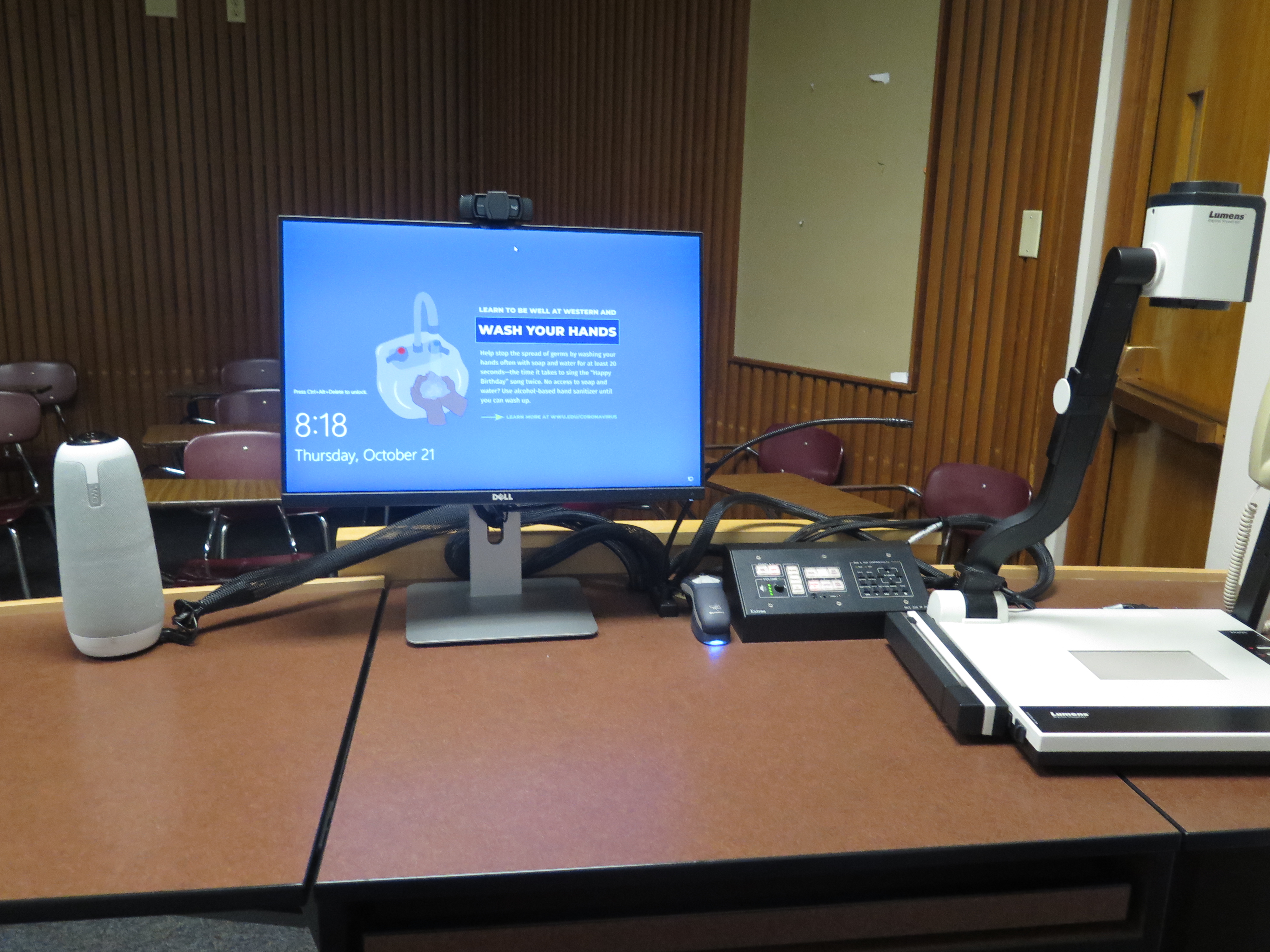 Top of the podium has a Lumens document camera, Dell PC Monitor, AV push button Controller, Owl Camera, and a Logitech Webcam
