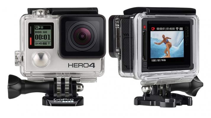 View of GoPro Hero 4 shows front of camera with the lens on the left side of device and record button just below that. Backside of camera shows screen where the menu is located.