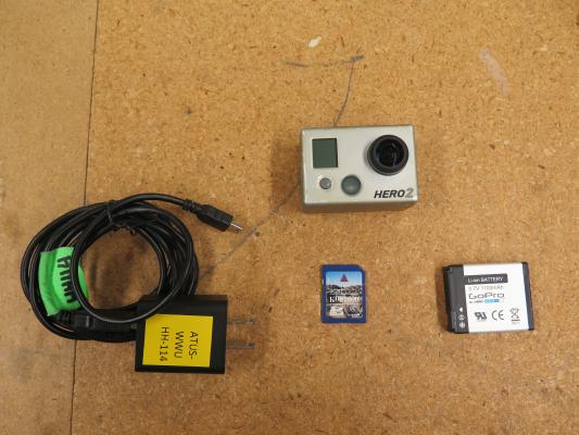 Image shows GoPro, power cable/ charger, SD card, and extra battery.